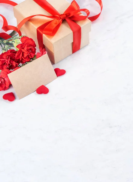 Mayo madres día hecho a mano regalos cuadro desea fotografía - Hermosos claveles en flor con caja de lazo de cinta roja aislado en el escritorio de mármol moderno, primer plano, espacio para copiar, maqueta —  Fotos de Stock