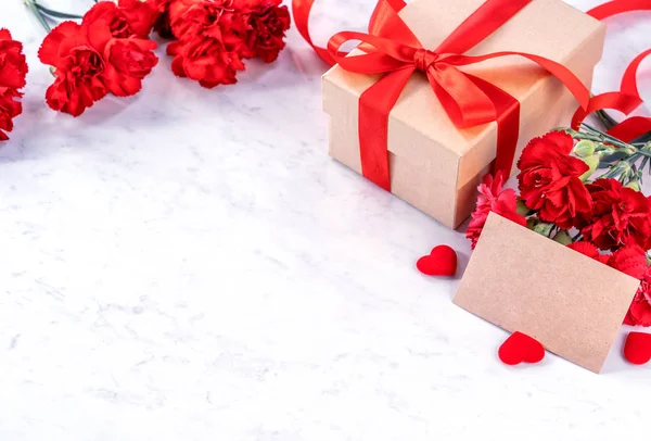 May mothers day handmade giftbox wishes photography - Beautiful blooming carnations with red ribbon bow box isolated on modern marble desk, close up, copy space, mock up — Stock Photo, Image