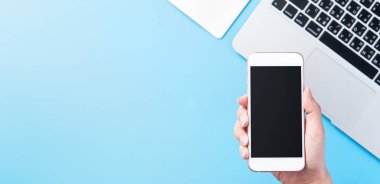 Bir kadın minimal mavi masa ile izole bir akıllı telefon tutuyor, online alışveriş ödeme kavramı, evde internet çalışması, e-ticaret, kopya alanı, düz yatıyordu, üst görünüm, alay