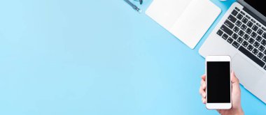 Bir kadın minimal mavi masa ile izole bir akıllı telefon tutuyor, online alışveriş ödeme kavramı, evde internet çalışması, e-ticaret, kopya alanı, düz yatıyordu, üst görünüm, alay