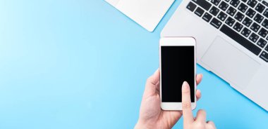 Bir kadın minimal mavi masa ile izole bir akıllı telefon tutuyor, online alışveriş ödeme kavramı, evde internet çalışması, e-ticaret, kopya alanı, düz yatıyordu, üst görünüm, alay