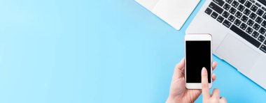 Bir kadın minimal mavi masa ile izole bir akıllı telefon tutuyor, online alışveriş ödeme kavramı, evde internet çalışması, e-ticaret, kopya alanı, düz yatıyordu, üst görünüm, alay