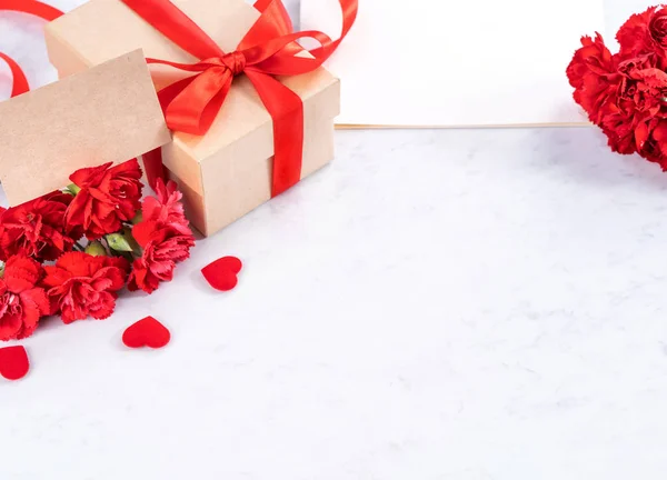 Maio mães dia handmade giftbox deseja fotografia - Cravos florescendo bonita com caixa de arco fita vermelha isolada na mesa de mármore moderno, close-up, espaço de cópia, mock up — Fotografia de Stock