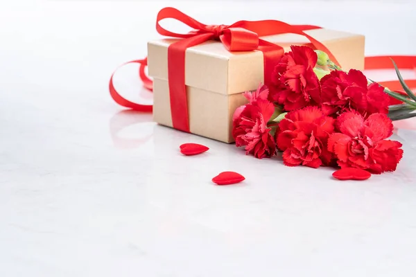 Maio mães dia handmade giftbox deseja fotografia - Cravos florescendo bonita com caixa de arco fita vermelha isolada na mesa de mármore moderno, close-up, espaço de cópia, mock up — Fotografia de Stock
