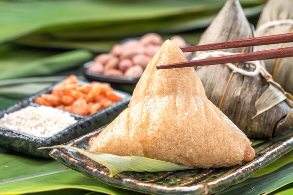 Close up, espaço de cópia, comida saborosa chinesa famosa no festival de barco dragão (duan wu), bolinhos de arroz cozidos no vapor em forma de pirâmide envolto por folhas de bambu feitas com ingredientes crus de arroz pegajoso — Fotografia de Stock