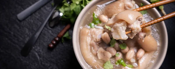 Vue de dessus, gros plan, espace de copie, nourriture de rue distinctive asiatique de Taiwan, soupe aux poings de porc aux arachides dans un bol beige ivoire crème-blanc isolé sur une table en ardoise de schiste foncé — Photo