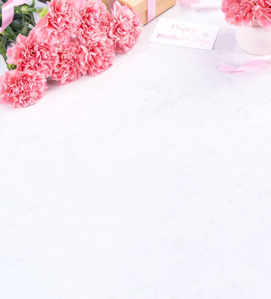 Design concept - Beautiful bunch of carnations on marble white background, top view, copy space, close up, mock up. Mothers day gift idea inspiration.