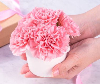 Tasarım konsepti - Kadın mermer beyaz arka plan, üst görünüm, kopya alanı, yakın, alay üzerine karanfil buket veren. Anneler günü fikir ilham.