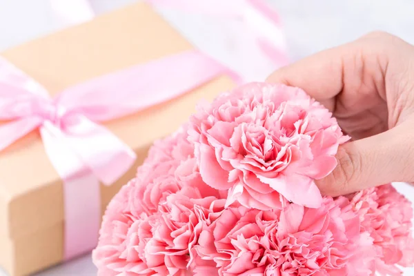 Design concept - Woman giving carnations bouquet on marble white background, top view, copy space, close up, mock up. Mothers day idea inspiration.