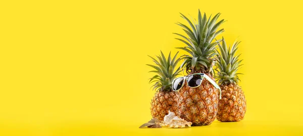 Креативное сосновое яблоко с солнцезащитными очками и оболочкой, изолированной на желтом фоне, дизайн идеи пляжа для летнего отдыха, пространство для копирования крупным планом — стоковое фото
