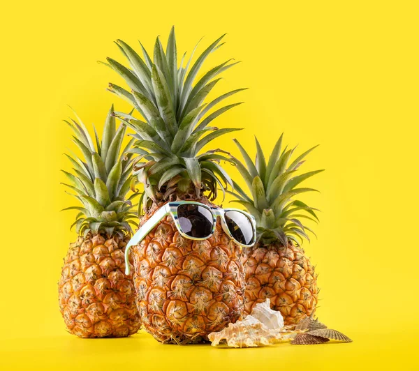Kreativ ananas tittar upp med solglasögon och skal isolerade på gul bakgrund, sommarsemester strand idé designmönster, kopiera utrymme närbild — Stockfoto