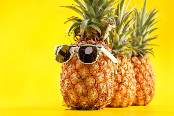 Ananas creativo guardando in su con occhiali da sole e guscio isolato su sfondo giallo, modello di progettazione idea spiaggia vacanza estiva, copiare lo spazio da vicino — Foto Stock