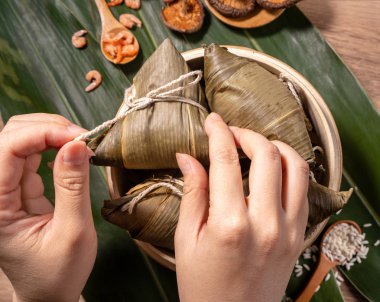 Zongzi, ahşap masada buğulanmış pirinç köftesi yiyen kadın, ejderha teknesi festivali Duanwu konseptinde yemek, kapan, kopyalama alanı, üst manzara, düz yatış.