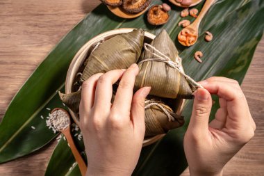 Zongzi, ahşap masada buğulanmış pirinç köftesi yiyen kadın, ejderha teknesi festivali Duanwu konseptinde yemek, kapan, kopyalama alanı, üst manzara, düz yatış.