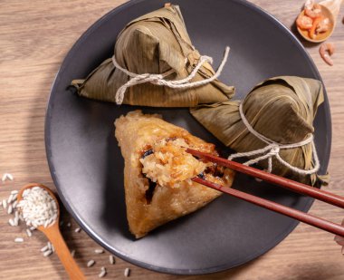 Zongzi, ahşap masada buğulanmış pirinç köftesi yiyen kadın, ejderha teknesi festivali Duanwu konseptinde yemek, kapan, kopyalama alanı, üst manzara, düz yatış.