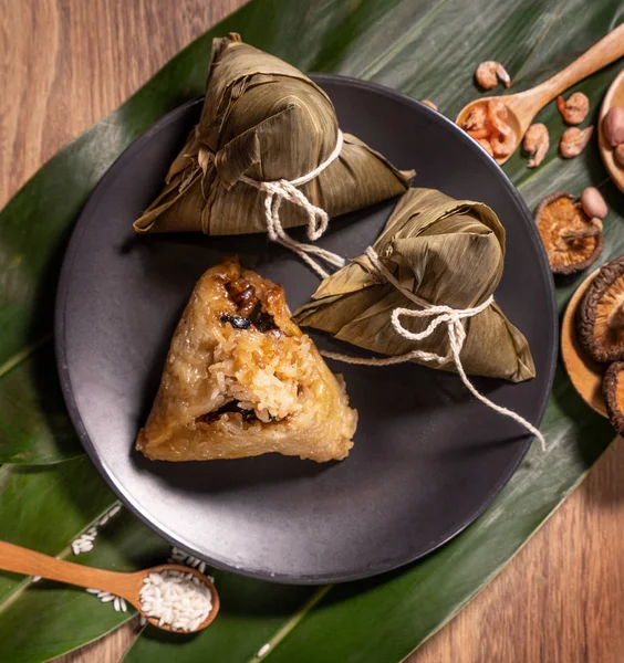 stock image Zongzi, steamed rice dumplings on wooden table bamboo leaves, food in dragon boat festival duanwu concept, close up, copy space, top view, flat lay