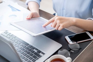 İş konsepti. Ofis masasında dijital cihaz ile proje için tablet kullanan kadın. Arka aydınlatma, güneş parlama etkisi, yakın, yan görünüm, kopyalama alanı