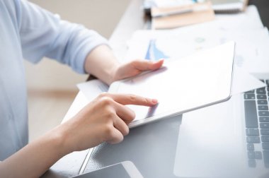 İş konsepti. Ofis masasında dijital cihaz ile proje için tablet kullanan kadın. Arka aydınlatma, güneş parlama etkisi, yakın, yan görünüm, kopyalama alanı