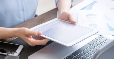İş konsepti. Ofis masasında dijital cihaz ile proje için tablet kullanan kadın. Arka aydınlatma, güneş parlama etkisi, yakın, yan görünüm, kopyalama alanı