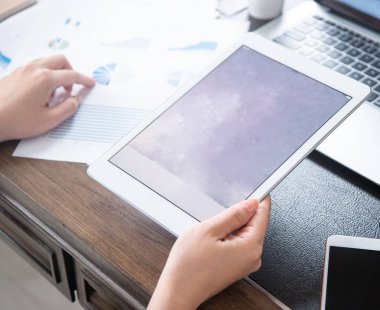 İş konsepti. Ofis masasında dijital cihaz ile proje için tablet kullanan kadın. Arka aydınlatma, güneş parlama etkisi, yakın, yan görünüm, kopyalama alanı