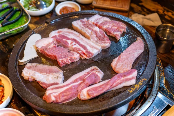Smažená černá vepřová moučka v korejské restauraci, čerstvá lahodná Korejská potravinářská kuchyně na železné desce s hlávkovým salátem, těsná, kopírovací, životní styl — Stock fotografie