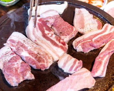 Kore restoranında tavada siyah domuz yemeği, marul ile demir tabakta taze lezzetli Kore yemekleri mutfağı, yakın çekim, kopya alanı, yaşam tarzı