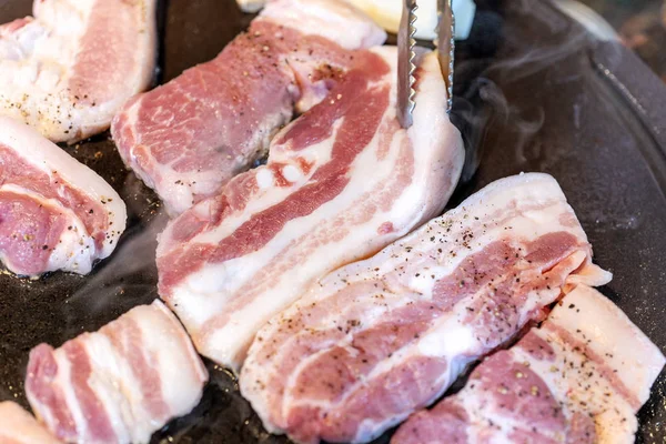 Pan-fried black pork meal in Korea restaurant, fresh delicious korean food cuisine on iron plate with lettuce, close up, copy space, lifestyle