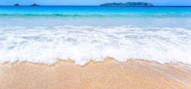 Güneşli mavi gökyüzü ile izole edilmiş yumuşak dalgaları olan harika, altın renkli kumlu plaj. Tropikal sakin turizm fikri, kopyala alanı, kapat