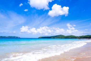 Güneşli mavi gökyüzü ile izole edilmiş yumuşak dalgaları olan harika, altın renkli kumlu plaj. Tropikal sakin turizm fikri, kopyala alanı, kapat