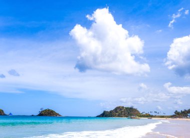 Güneşli mavi gökyüzü ile izole edilmiş yumuşak dalgaları olan harika, altın renkli kumlu plaj. Tropikal sakin turizm fikri, kopyala alanı, kapat