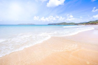 Güneşli mavi gökyüzü ile izole edilmiş yumuşak dalgaları olan harika, altın renkli kumlu plaj. Tropikal sakin turizm fikri, kopyala alanı, kapat