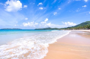 Güneşli mavi gökyüzü ile izole edilmiş yumuşak dalgaları olan harika, altın renkli kumlu plaj. Tropikal sakin turizm fikri, kopyala alanı, kapat