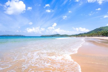 Güneşli mavi gökyüzü ile izole edilmiş yumuşak dalgaları olan harika, altın renkli kumlu plaj. Tropikal sakin turizm fikri, kopyala alanı, kapat