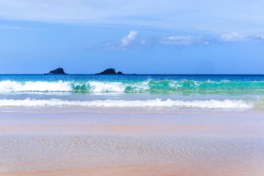 Güneşli mavi gökyüzü ile izole edilmiş yumuşak dalgaları olan harika, altın renkli kumlu plaj. Tropikal sakin turizm fikri, kopyala alanı, kapat