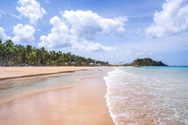 Güneşli mavi gökyüzü ile izole edilmiş yumuşak dalgaları olan harika, altın renkli kumlu plaj. Tropikal sakin turizm fikri, kopyala alanı, kapat