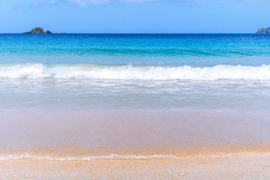 Güneşli mavi gökyüzü ile izole edilmiş yumuşak dalgaları olan harika, altın renkli kumlu plaj. Tropikal sakin turizm fikri, kopyala alanı, kapat