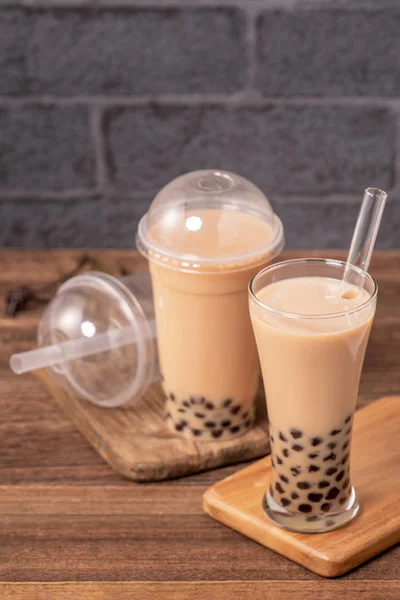 Delicious bubble milk tea with straw in drinking glass on wooden table background, concept of reduce plastic to go in Taiwan, close up, copy space