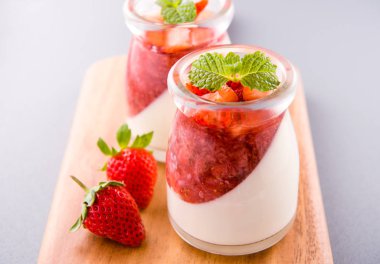 Havadar mavi arka plan, kopya alanı, yakın izole nane ve doğranmış sarkokus tepesi ile delikoz ve besleyici çift renkli (renkli) çilek tatlılar