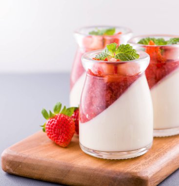 Havadar mavi arka plan, kopya alanı, yakın izole nane ve doğranmış sarkokus tepesi ile delikoz ve besleyici çift renkli (renkli) çilek tatlılar