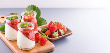 Havadar mavi arka plan, kopya alanı, yakın izole nane ve doğranmış sarkokus tepesi ile delikoz ve besleyici çift renkli (renkli) çilek tatlılar