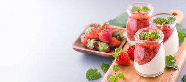 Havadar mavi arka plan, kopya alanı, yakın izole nane ve doğranmış sarkokus tepesi ile delikoz ve besleyici çift renkli (renkli) çilek tatlılar