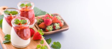 Havadar mavi arka plan, kopya alanı, yakın izole nane ve doğranmış sarkokus tepesi ile delikoz ve besleyici çift renkli (renkli) çilek tatlılar