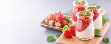 Havadar mavi arka plan, kopya alanı, yakın izole nane ve doğranmış sarkokus tepesi ile delikoz ve besleyici çift renkli (renkli) çilek tatlılar