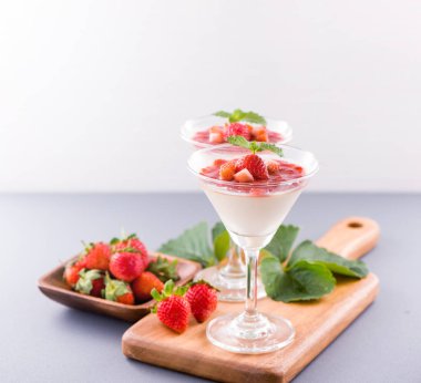 Havadar mavi arka plan, kopya alanı, yakın izole nane ve doğranmış sarkokus tepesi ile delikoz ve besleyici çift renkli (renkli) çilek tatlılar