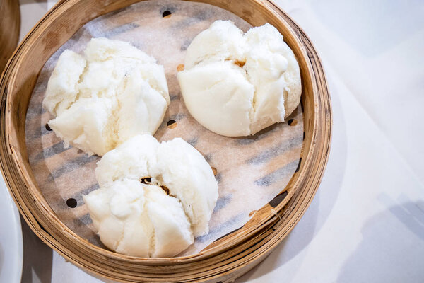 Delicious dim sum, famous cantonese food in asia - Fresh and hot Cha Siu Bao, BBQ pork bun in bamboo steamer in hong kong yumcha restaurant, close up
