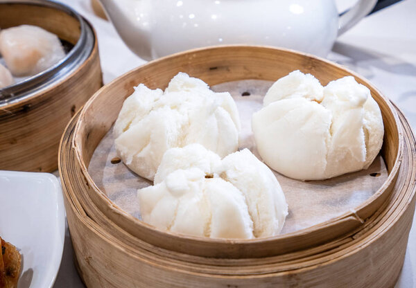 Delicious dim sum, famous cantonese food in asia - Fresh and hot Cha Siu Bao, BBQ pork bun in bamboo steamer in hong kong yumcha restaurant, close up