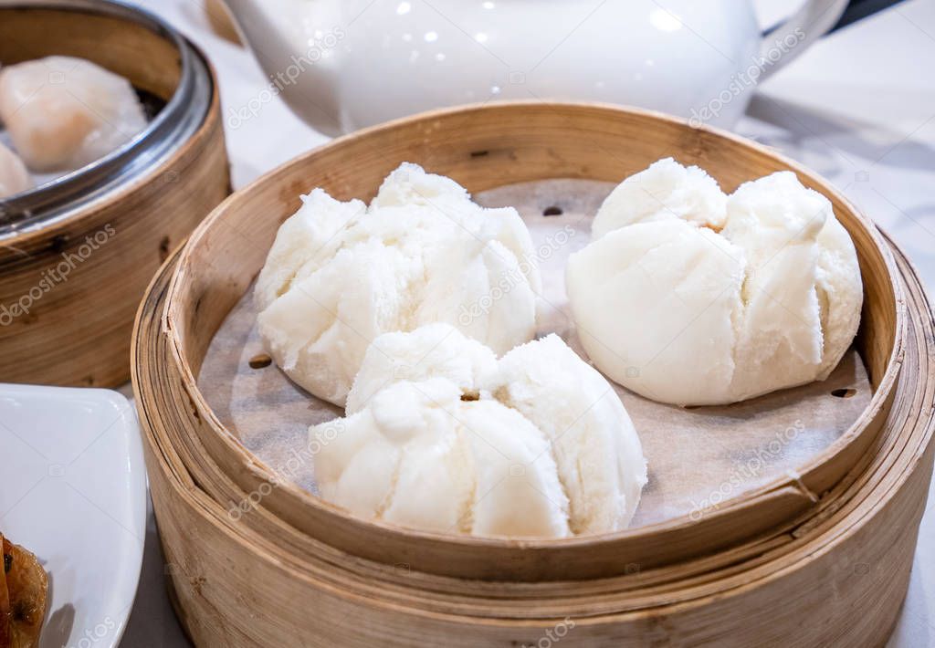 Delicious dim sum, famous cantonese food in asia - Fresh and hot Cha Siu Bao, BBQ pork bun in bamboo steamer in hong kong yumcha restaurant, close up