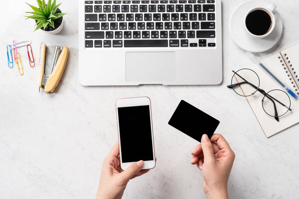 Женщина делает онлайн покупку, макет кредитной карты и мобильного телефона на рабочем столе изолированы на красивом мраморном фоне моды, копировальное пространство, вид сверху, плоский план, крупный план
