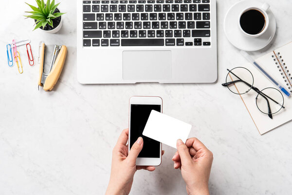 Женщина делает онлайн покупку, макет кредитной карты и мобильного телефона на рабочем столе изолированы на красивом мраморном фоне моды, копировальное пространство, вид сверху, плоский план, крупный план
