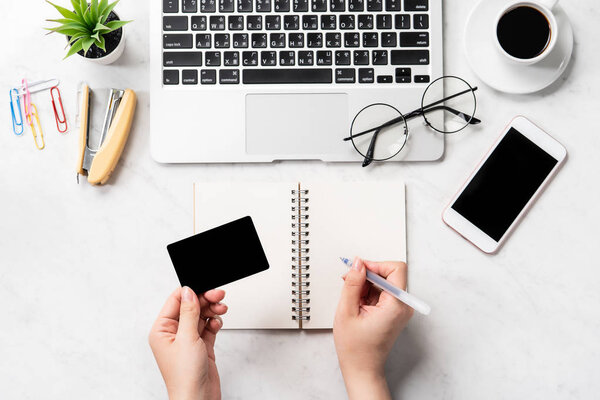 Женщина делает онлайн покупку, макет кредитной карты и мобильного телефона на рабочем столе изолированы на красивом мраморном фоне моды, копировальное пространство, вид сверху, плоский план, крупный план
